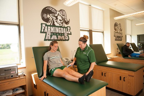 Assistant athletic trainer Jessica Dautner treating student-athlete who is laying on table.